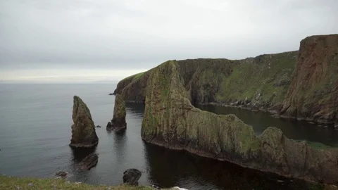 Scottish cliff face with sea stacks showing long term coastal erosion Stock Footage 114412675