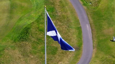 Scottish flag waving in wind on top of golf course hill with lush green lan.. Stock Footage 337770751