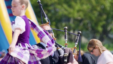 Scottish Highland Dancer Performs to Live Bagpipe Music Outdoors Stock Footage 314712107