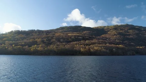 Scottish mountain in sunshine with main road and colourful trees Stock Footage 102394810