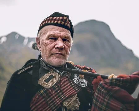 Scottish piper posing in the highlands Stock Photos