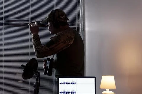 A scout or analyst in the process of surveillance indoors: laptop, microphone 스톡 사진