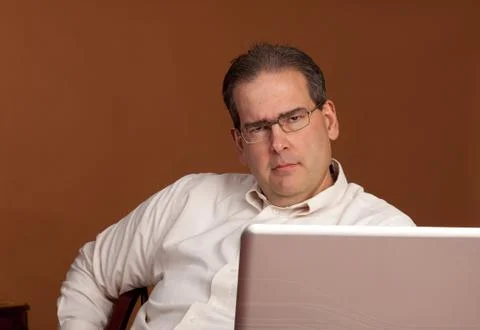 Scowling middle age man at computer Stock Photos