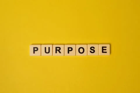 Scrabble letters with text PURPOSE isolated on a yellow background Stock Photos