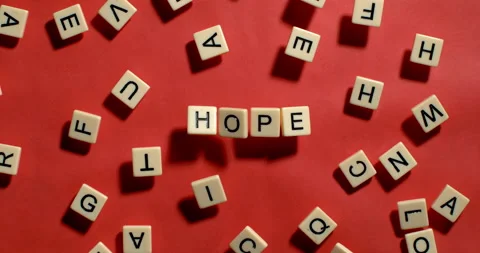 Scrabble tiles fall in slow motion to spell Hope on Red background Video stock 254037489