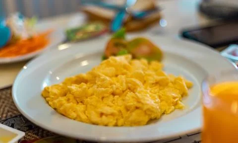 Scrambled egg presented on a white plate at breakfast table. Healthy Breakfas Stock Photos