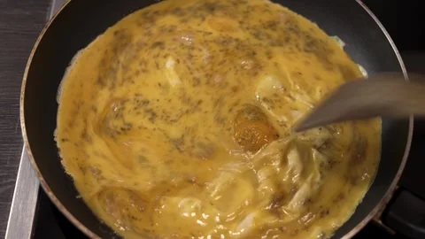 Scrambled egg yolk with herbs in hot pan getting stirred Stock Footage 268418137