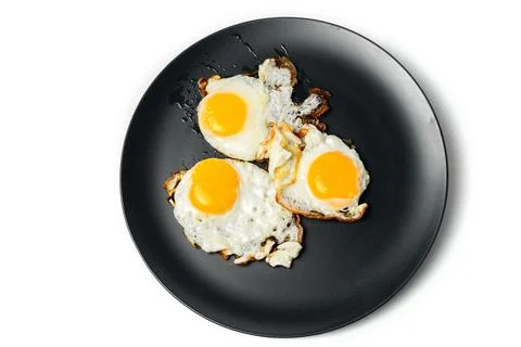 Scrambled eggs from 3 eggs on gray plates on white background Stock Photos