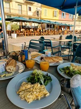 Scrambled eggs and salad breakfast on outdoor cafe table Stock Photos