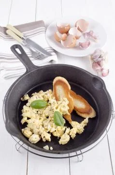Scrambled eggs and toasted bread in a pan Stock Photos