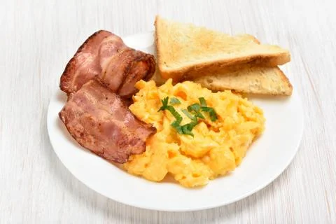 Scrambled eggs with bacon and toasts Stock Photos