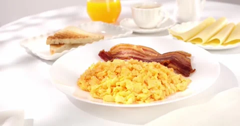 Scrambled eggs with bacon and tomato. breakfast on a white plate. Stock Footage 244908443