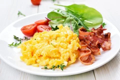 Scrambled eggs, bacon and vegetable salad Stock Photos
