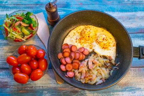 Scrambled eggs with bacon, onion and sausage. Stock Photos