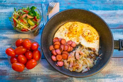 Scrambled eggs with bacon, onion and sausage. Stock Photos
