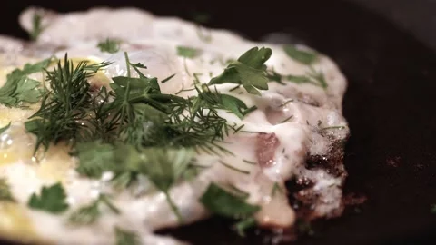 Scrambled eggs with bacon slices and herbs are fried on the stove Stock Footage 146335232