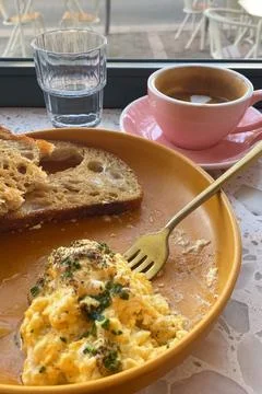 Scrambled eggs with bread and coffee on table in cafe Stock Photos