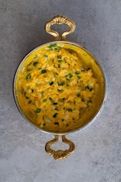 Scrambled eggs with cheese and spring onion. Served in a copper pan. Stock Photos