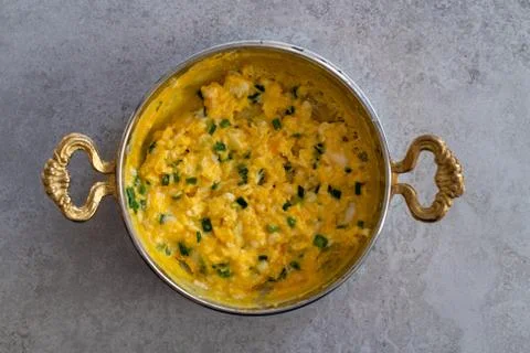 Scrambled eggs with cheese and spring onion. Served in a copper pan. Stock Photos