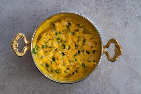Scrambled eggs with cheese and spring onion. Served in a copper pan. Stock Photos