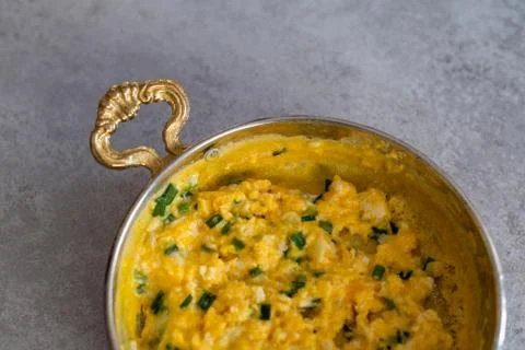 Scrambled eggs with cheese and spring onion. Served in a copper pan. Stock Photos