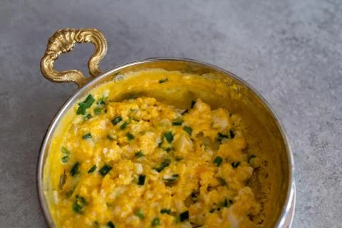 Scrambled eggs with cheese and spring onion. Served in a copper pan. Stock Photos
