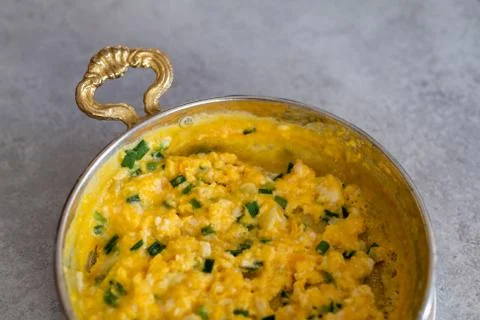 Scrambled eggs with cheese and spring onion. Served in a copper pan. Stock Photos