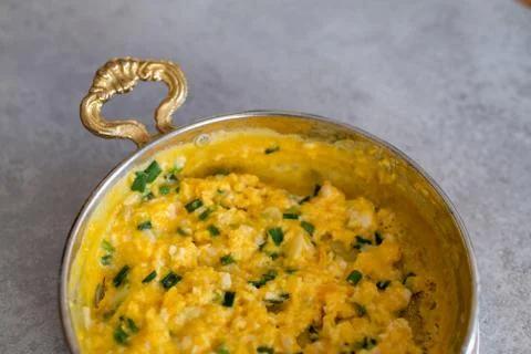 Scrambled eggs with cheese and spring onion. Served in a copper pan. Stock Photos