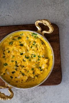 Scrambled eggs with cheese and spring onion. Served in a copper pan. Stock Photos