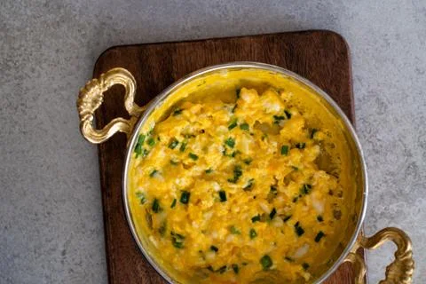 Scrambled eggs with cheese and spring onion. Served in a copper pan. Stock Photos