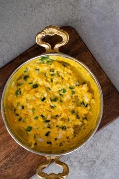 Scrambled eggs with cheese and spring onion. Served in a copper pan. Stock Photos