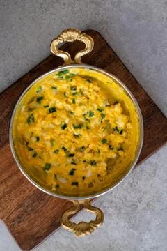 Scrambled eggs with cheese and spring onion. Served in a copper pan. Stock Photos