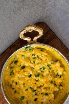 Scrambled eggs with cheese and spring onion. Served in a copper pan. Stock Photos