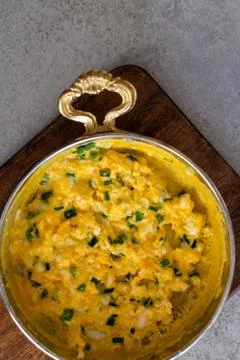 Scrambled eggs with cheese and spring onion. Served in a copper pan. Stock Photos