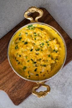 Scrambled eggs with cheese and spring onion. Served in a copper pan. Stock Photos