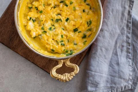 Scrambled eggs with cheese and spring onion. Served in a copper pan. Stock Photos