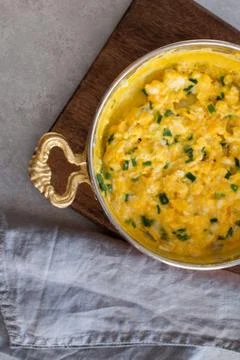 Scrambled eggs with cheese and spring onion. Served in a copper pan. Stock Photos