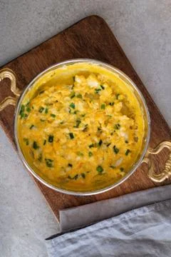 Scrambled eggs with cheese and spring onion. Served in a copper pan. Stock Photos