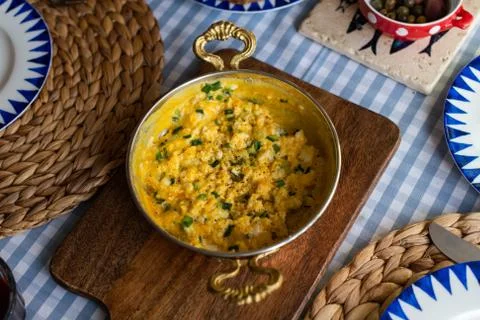 Scrambled eggs with cheese and spring onion. Served in a copper pan. Stock Photos