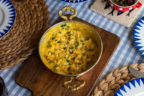 Scrambled eggs with cheese and spring onion. Served in a copper pan. Stock Photos