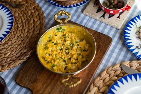 Scrambled eggs with cheese and spring onion. Served in a copper pan. Stock Photos