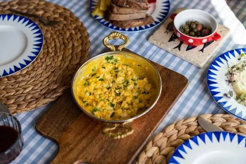 Scrambled eggs with cheese and spring onion. Served in a copper pan. Stock Photos