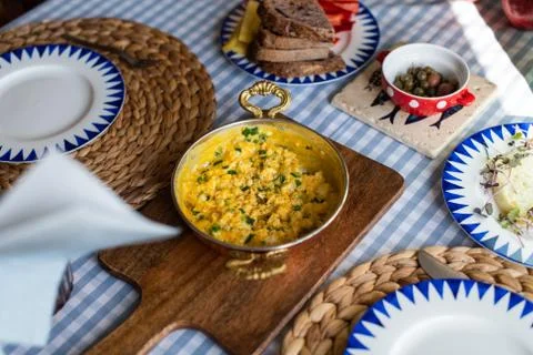 Scrambled eggs with cheese and spring onion. Served in a copper pan. Stock Photos