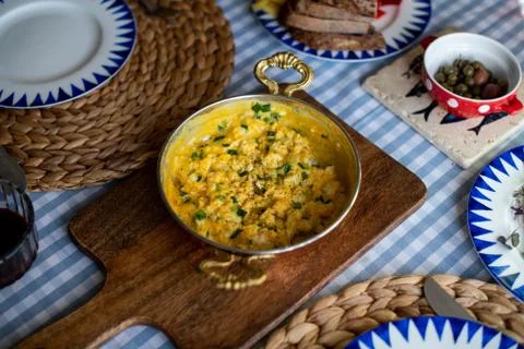Scrambled eggs with cheese and spring onion. Served in a copper pan. Stock Photos