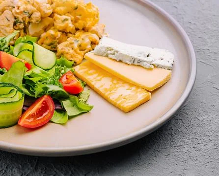 Scrambled eggs with cheese and tomato and cucumber salad Stock Photos