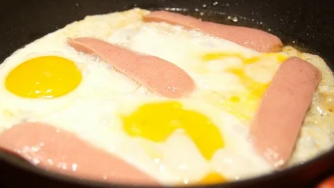 Scrambled eggs cooking. Chef cooking omelette. Eggs and sausages frying Stock Footage 100107254