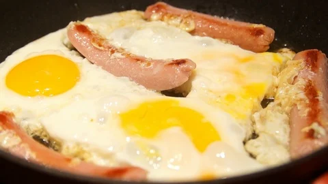 Scrambled eggs cooking. Chef cooking omelette. Eggs and sausages frying Stock Footage 100107419