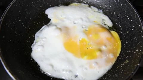 Scrambled eggs cooking. One egg being fried on a frying pan Stock Footage 140029840