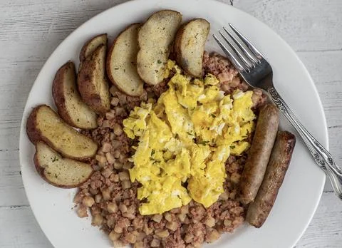 Scrambled eggs on corn beef hash,  with sausage and potatoes 스톡 사진