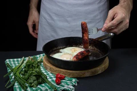 Scrambled eggs on a dark background. Fried eggs with fried sausages. Stock Photos
